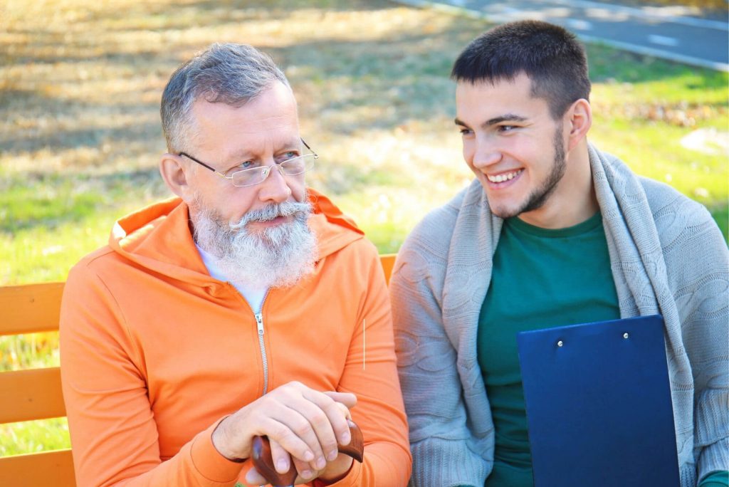 Young man sitting on a park bench with an older man.
