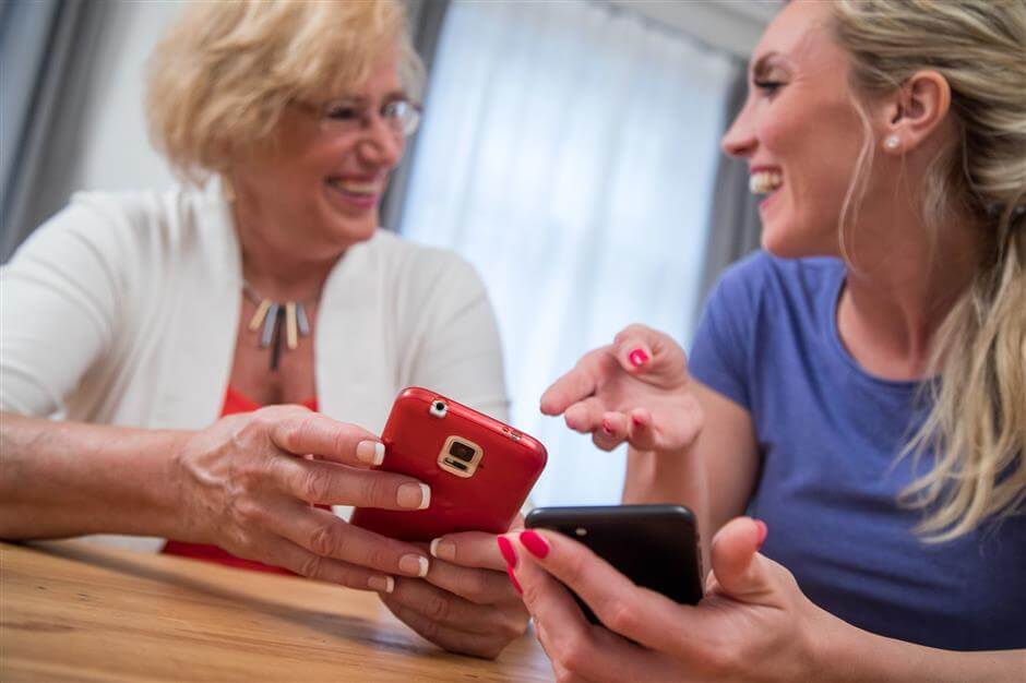 younger woman and an older woman using mobile phones together.