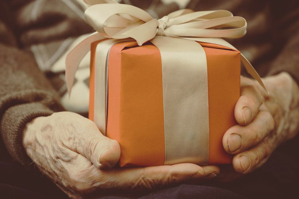 older man's hands holding a wrapped gift.