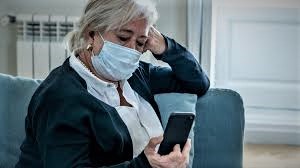 woman wearing a medical face mask and reading her mobile phone